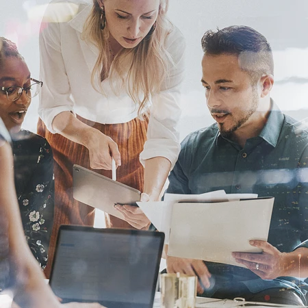 Team in moderner Büroumgebung arbeitet mit Tablet und Laptop, überlagert von urbanen Lichtreflexionen als Symbol für digitale Transformation der Arbeitswelt.