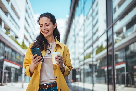 Frau mit Smartphone vor einem modernen Gebäude in der Stadt.