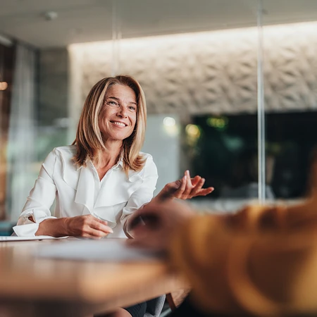 Frau im Business-Outfit bei einem Meeting mit Laptop und Dokumenten