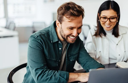 Mann und Frau arbeiten gemeinsam an einem Laptop im Büro