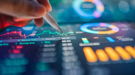 Hand mit einem digitalen Stift, der auf Finanzdiagramme und Datenvisualisierungen auf einem Tablet zeigt.