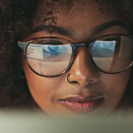 Nahaufnahme einer Frau mit Brille, in deren Gläsern ein Computerbildschirm reflektiert wird: Genau hinsehen lohnt sich!