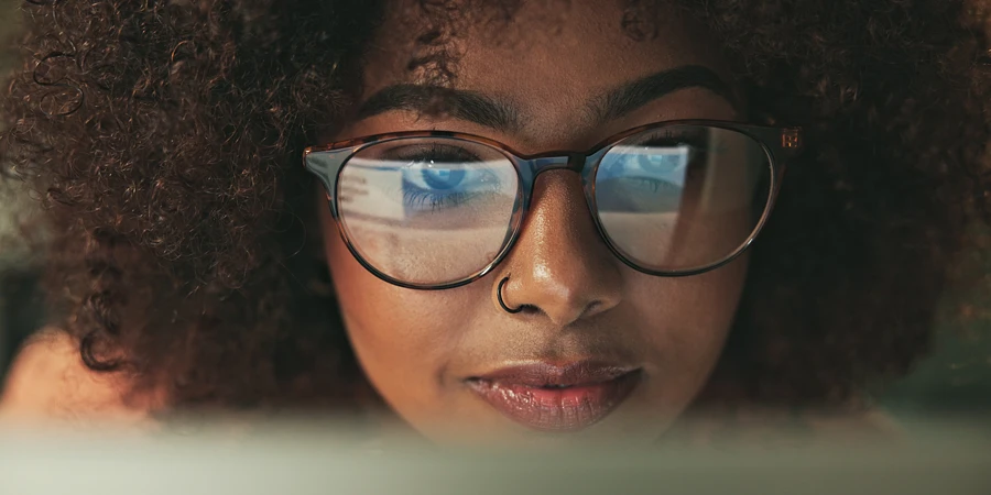 Nahaufnahme einer Frau mit Brille, in deren Gläsern ein Computerbildschirm reflektiert wird: Genau hinsehen lohnt sich!