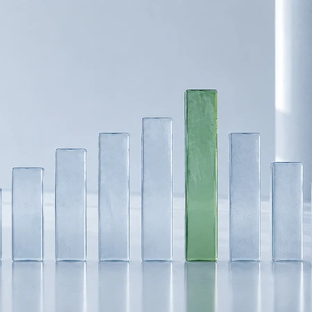 Reihe von transparenten Glasblöcken in verschiedenen Höhen, ein grüner Block steht im Zentrum.